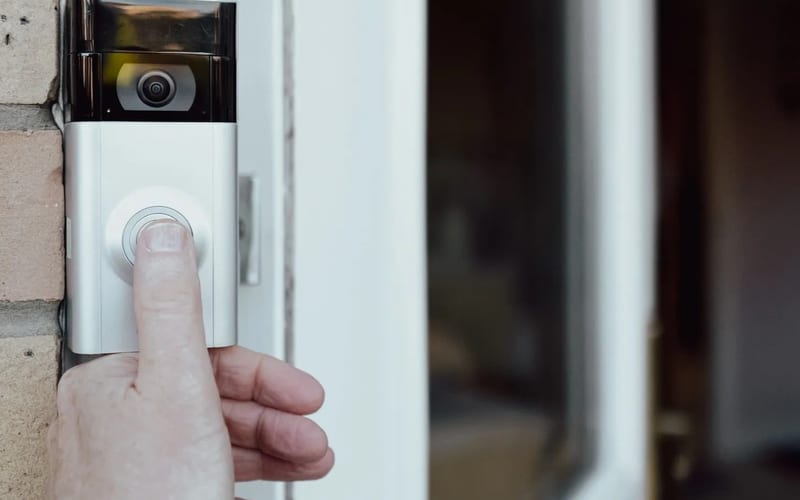 Hand pressing a smart doorbell camera button